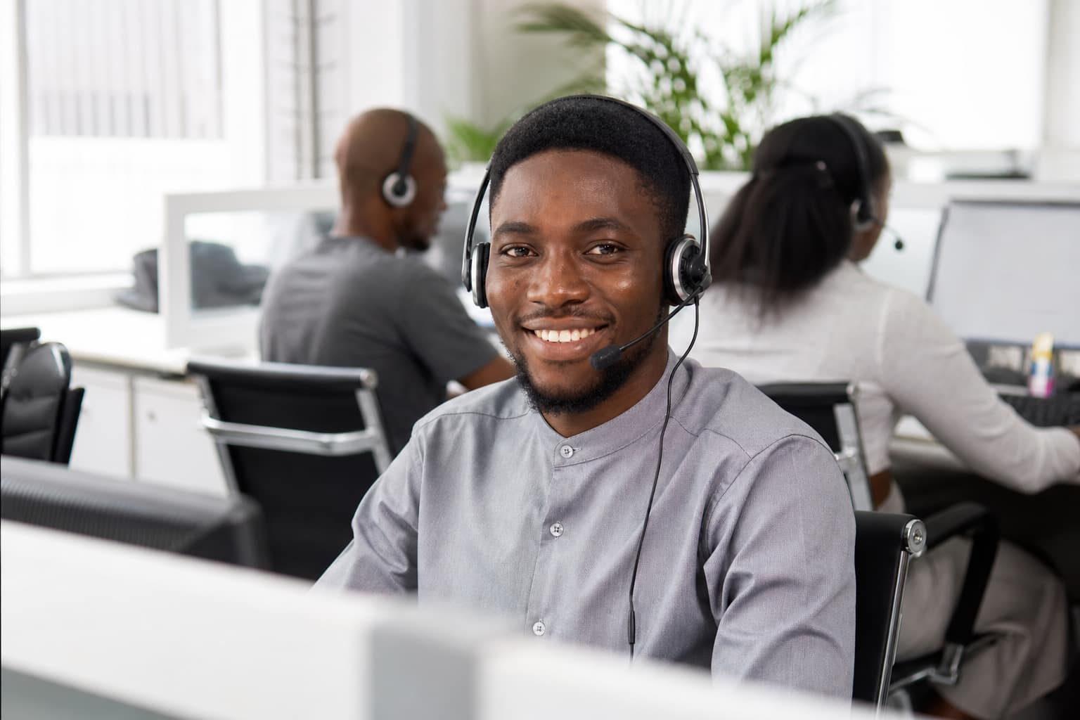 GoodGoods Nigerian male call center agent wearing a headset in a bright office